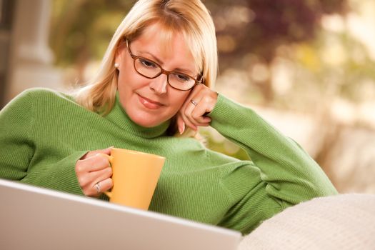 Beautiful, Smiling Woman Enjoys Her Warm Drink and Laptop Relaxing Day.