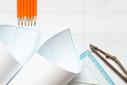 Divider, pencils and ruler on blue graph paper background