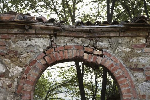 Dilapidated stone archway with trees in background in Tuscany, Italy.