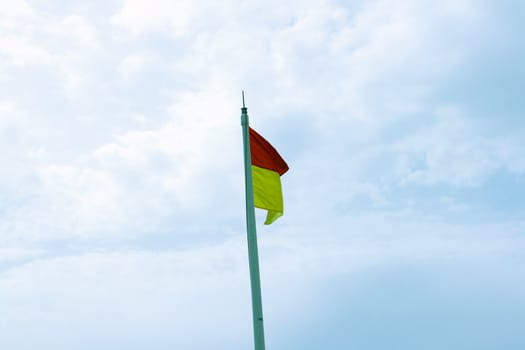 Beach warning flag flying against a blue sky