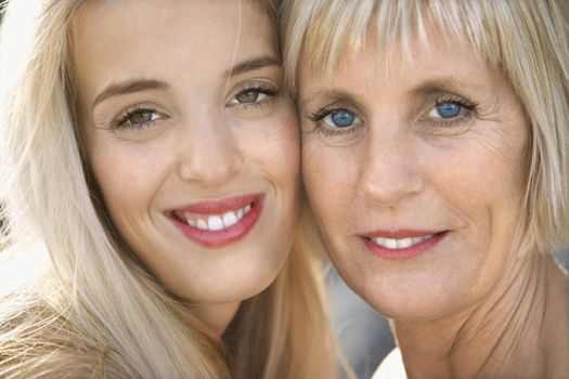 Portrait of Caucasian mother and daughter smiling looking at viewer.