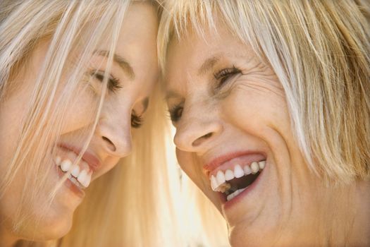 Portrait of Caucasian mother and daughter laughing and looking at each other.