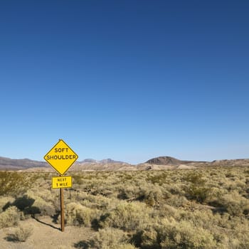 Road sign in desert for soft shoulder and mountains in distance.