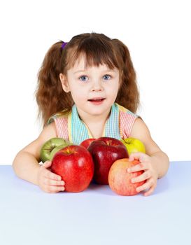 A little girl playing with apples sitting at the table