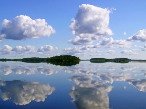 Smooth surface of water clouds are reflected in a surface of lake