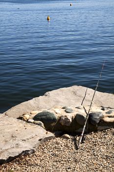 Abandoned fishing rod on the stones, near the sea