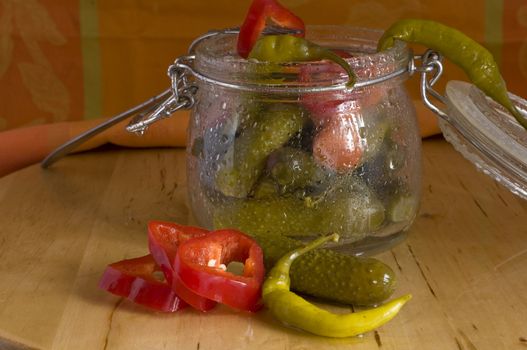 pickles assortment in a glass jar, on light wood background