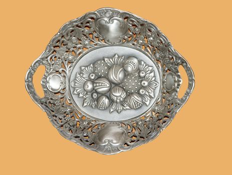 Silver decorative dish with ornament on orange background