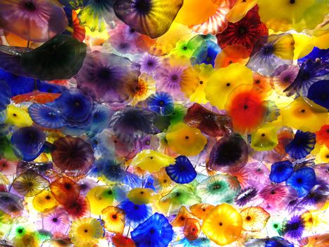 A modern glass ceiling that is made up of several glass flowers of all colors