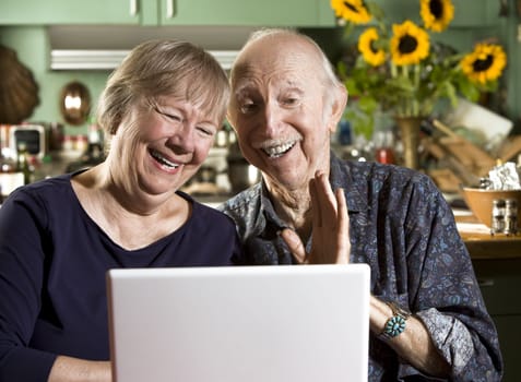 Smiling Senior Couple in their Dining Room with a Laptop Computer