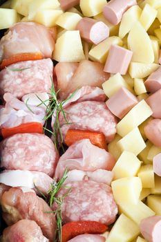 detail of raw pork kebab with sliced potatoes, wurstel and rosemary