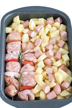 detail of raw pork kebab with sliced potatoes, wurstel and rosemary