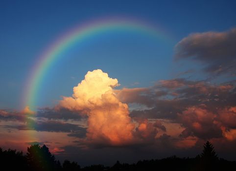 A photography of a white cloud in the evening sun under a rainbow