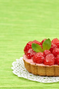 Fruit tartlet on white doily and green background