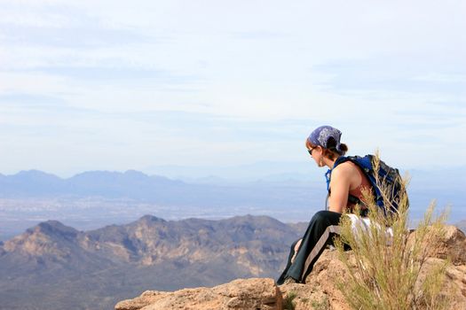 A yound girl admires the view after climbing to the top of a tall desert mountain