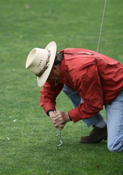 Man screwing a stake into the ground to secure a tent