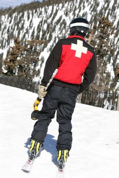 A ski patrol member carries a large drill to setup warning signs at a popular resort