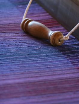 Beatiful fabric woven on an old fashion loom. Selective focus on the midsection.