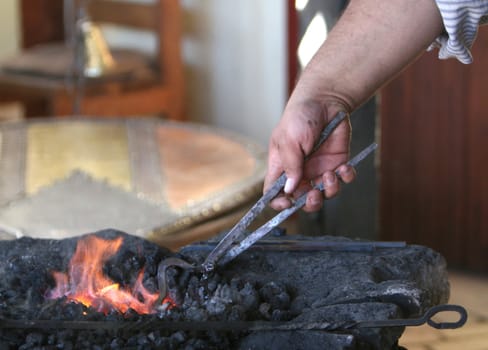A blacksmith heats steel in a hot fire