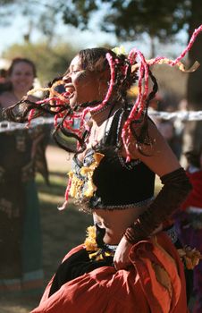 Young black woman playing jump rope at a festival. She is very happy and her braids are flying everywhere.