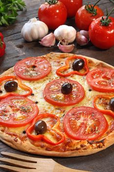 Tomato pizza with some ingredients behind