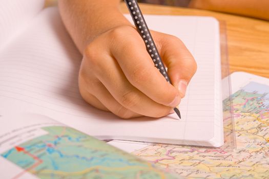 Girl doing her homework by writing in notebook. 