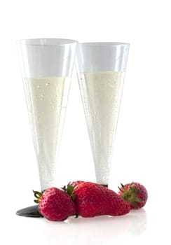 Two glasses of spumante and some strawberry on white background