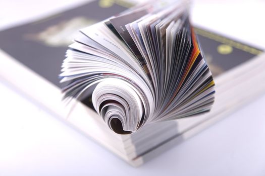 Magazine Roll isolated on white, on a bunch of other magazines 