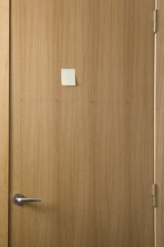 wooden door with a post-it stick on it