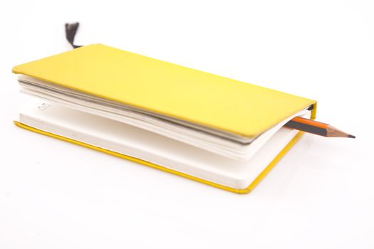 yellow notebook and pencil on  white background