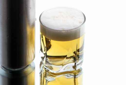 Closeup of beer glass and can on white background with reverberation