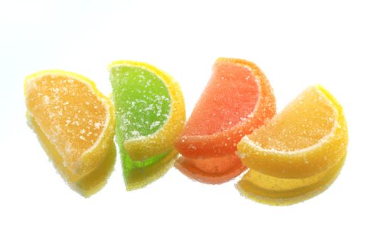 Few colored fruit jelly lying in a row on glass background with reverberation