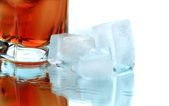 Glass of whiskey with ice cubes on white background with reverberation