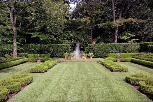 An english garden with a fountain spraying in the center