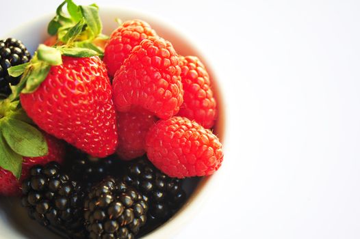 Blackberry, Raspberry and Strawberries isolated on a white background in a small white bowl.