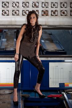 A young brazilian female model shot in a dirty auto repair shop.