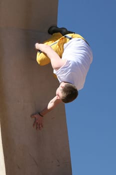 A teenager performing a Parkour stunt. He is running up a wall and flipping in the air.