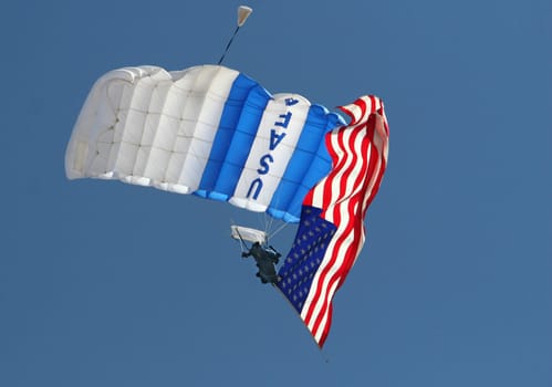 A USAF parachute jumper trails an american flag at an airshow