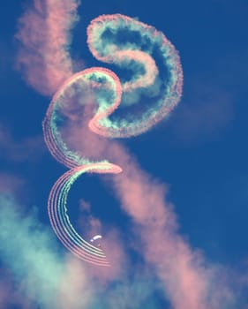 A  parachute jumper leave behind a trail of colorful smoke. At an airshow in Arizona.