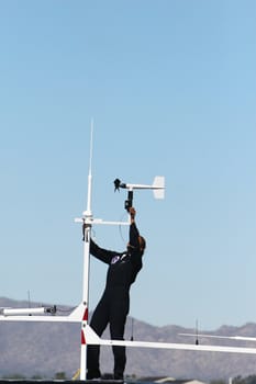 A moan attaches a wind vane to a portable weather and communication station used by the airforce