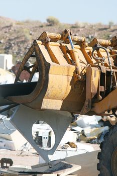 A bulldozer crushes and moves a giant stack of refrigerators, air conditioners, and stoves.