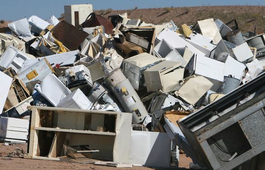 A pile of water heaters, air conditions, and other appliances at a waste dump