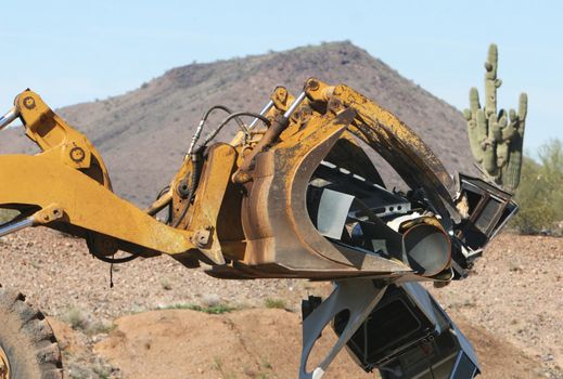 A bulldozer crushes and moves a giant stack of refrigerators, air conditioners, and stoves.