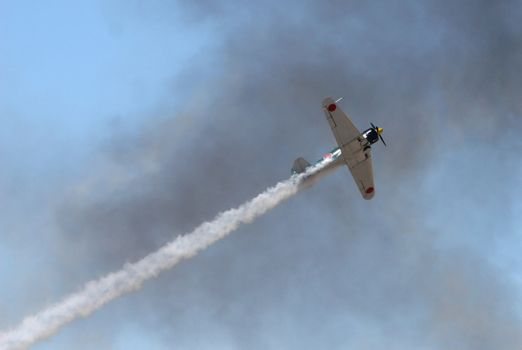 An old japanese warplane flys through heavy smoke during a simulated attack