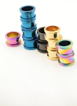 Five stacks of colorful titanium screw on flesh tunnels. These are used in stretched ear lobes.