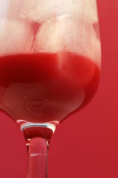 A delicious red cocktail drink on ice. Served in a tall stem daiquiri glass