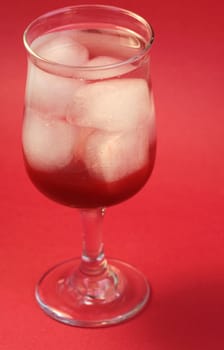 A delicious red cocktail drink on ice. Served in a tall stem daiquiri glass