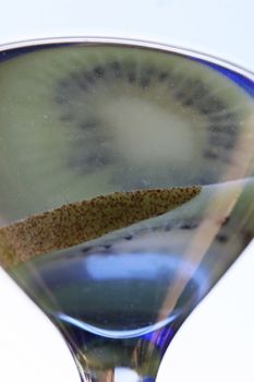 A delicious cocktail drink with a kiwi reflecting off the top surface.