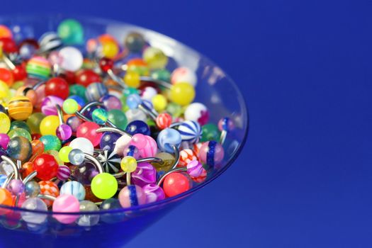 A martini glass full of navel rings. On Saturated Blue Background