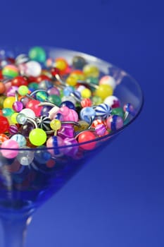 A martini glass full of navel rings. On Saturated Blue Background